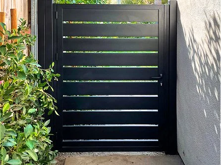 Powder-coated black ornamental iron fence beside a stucco wall